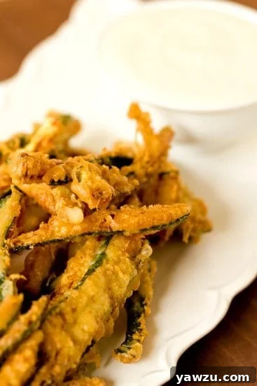 Crispy golden beer-battered zucchini fries piled high, ready to be enjoyed.