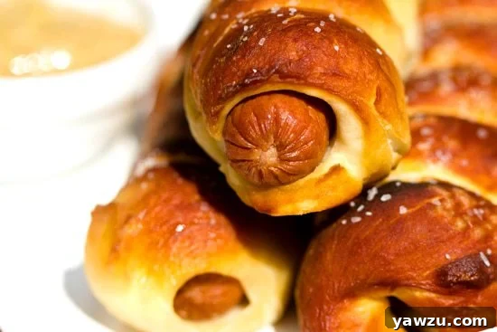 Freshly baked pretzel dogs cooling on a rack, showcasing their perfectly browned crust and a sprinkling of coarse salt.
