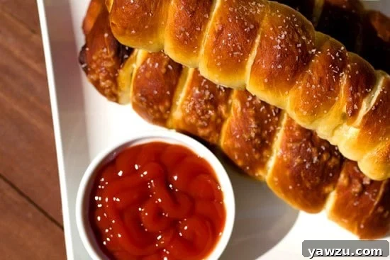 Platter of golden-brown pretzel dogs, garnished with parsley, served with various dipping sauces like mustard and ketchup, perfect for a party.