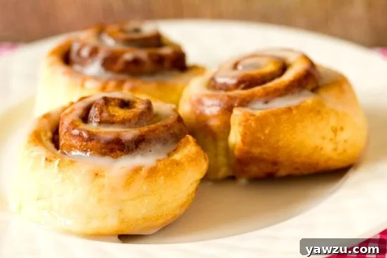 Baked Cinnamon Roll Biscuits arranged in a pie plate, freshly removed from the oven and glistening with icing.