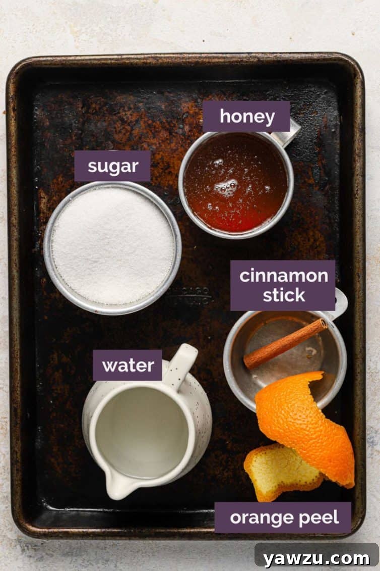 Ingredients for honey syrup laid out on a baking sheet with purple labels identifying each component.
