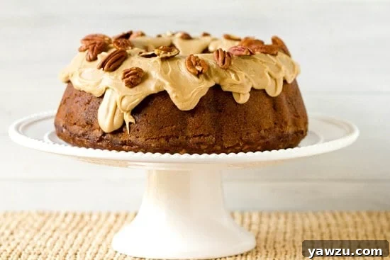 Slice of Apple Pecan Spice Cake showing the distinct cream cheese filling swirl and generous praline topping