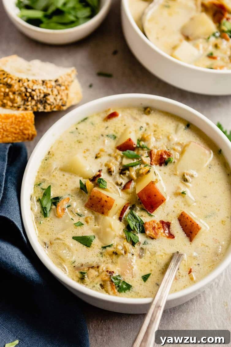A beautifully presented bowl of creamy New England clam chowder, garnished with fresh herbs, alongside crusty bread and a side salad, ready to be enjoyed.