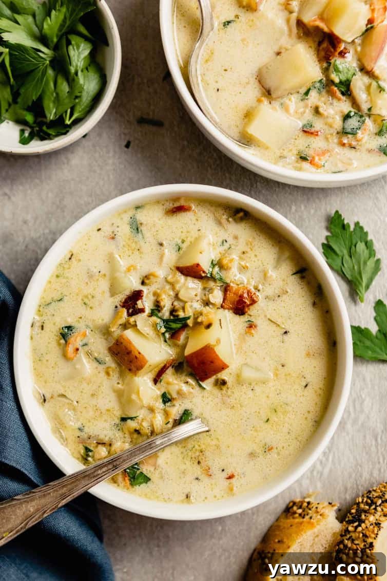 Two generous bowls of freshly made New England clam chowder, perfectly creamy and inviting, garnished with herbs and crispy bacon bits, ready for serving.