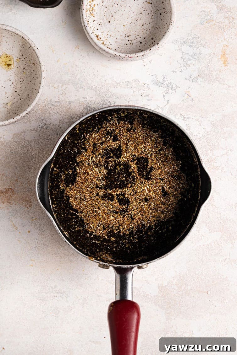 Herb oil for focaccia in a sauce pan on a white counter.