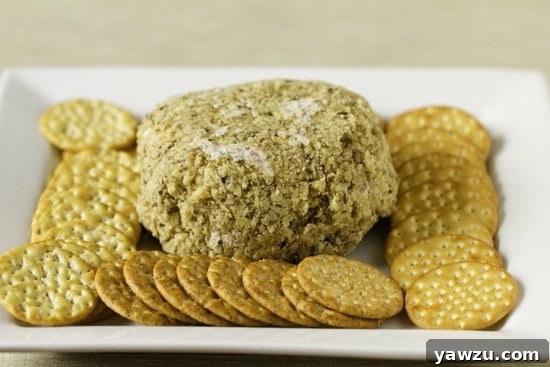 A perfectly formed pimiento cheese ball, ready to be served with crackers.