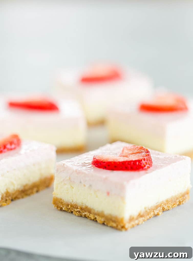 Multiple strawberry cheesecake bars sitting on parchment paper.