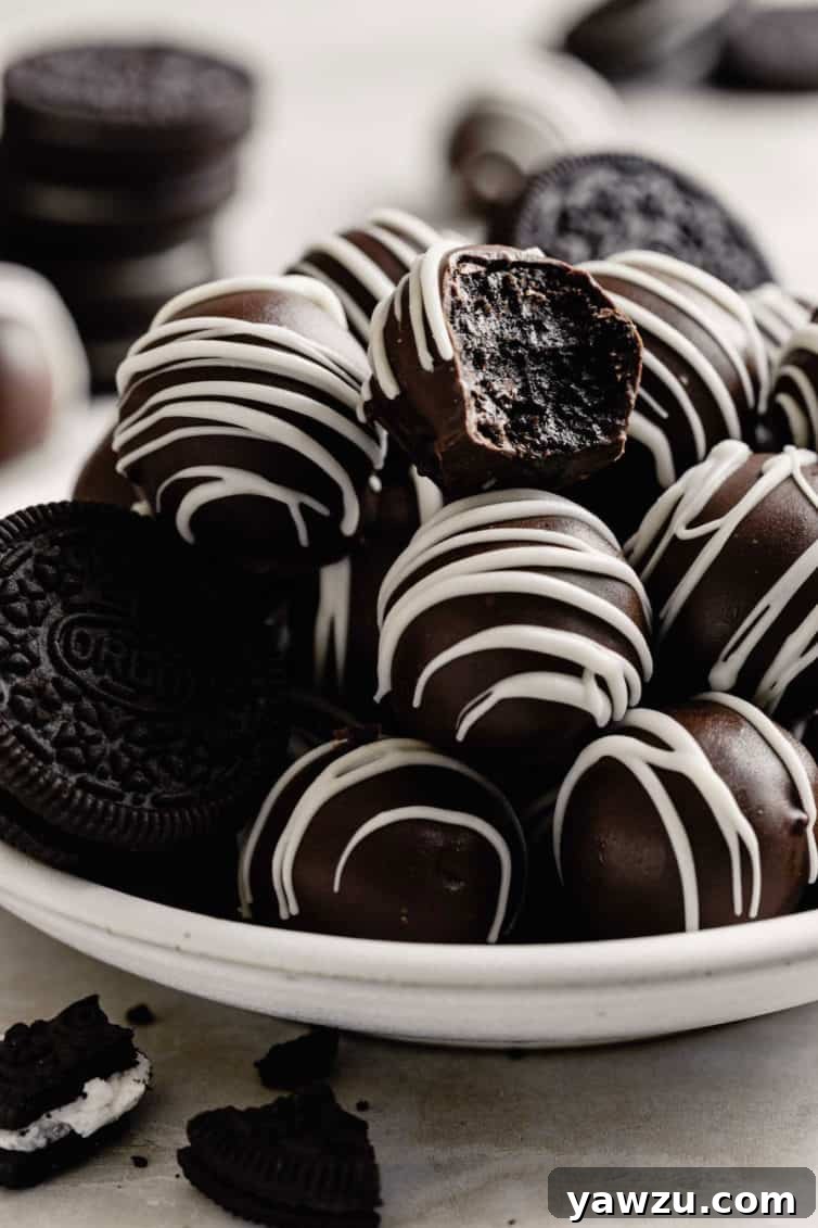 A pile of Oreo truffles on a plate with one bitten into.