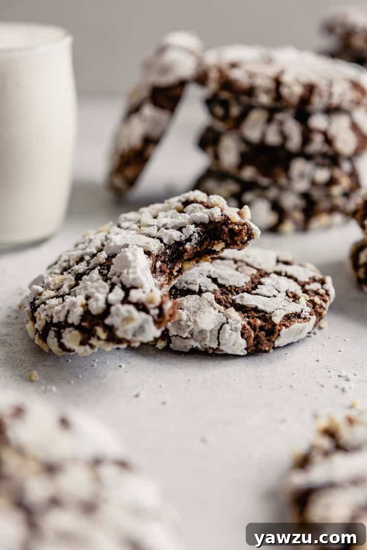 Half eaten Nutella cookie with others and glass of milk in the background.