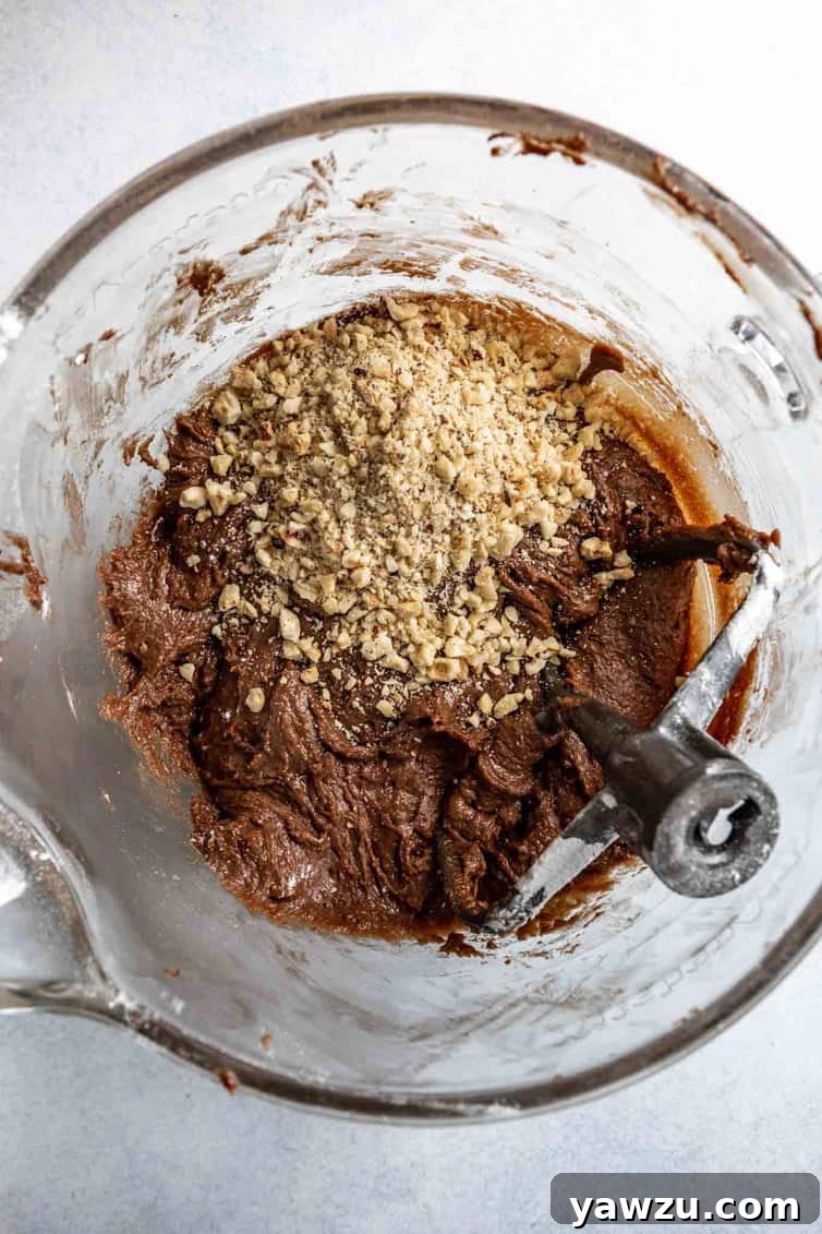 Nutella cookie dough in glass bowl with chopped hazelnuts on top.