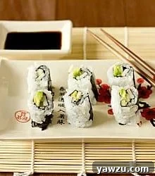 Sushi rolls on a white plate with chopsticks.
