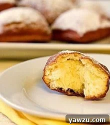 Half of a fluffy beignet on a white plate, revealing its airy interior texture.