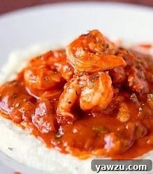 A serving of creole shrimp and grits in a white bowl, ready to be enjoyed.