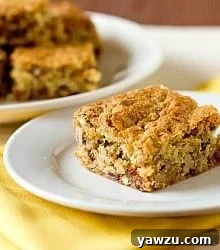 A perfectly baked Date-Nut Snack Cake bar on a white plate, ready to be enjoyed with a cup of coffee.
