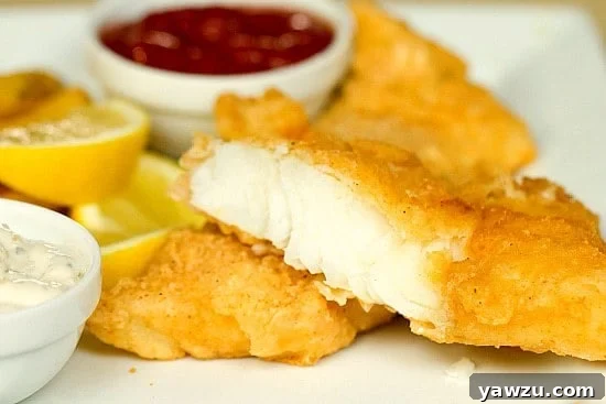Freshly fried beer battered cod, golden and crispy, ready to be served, highlighting its irresistible texture and inviting appearance.