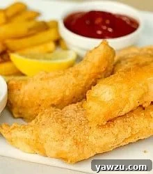 Beer battered cod and french fries on a white plate with lemon wedges, tartar sauce in a white bowl, and ketchup in a white bowl.