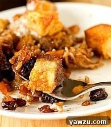 Serving of Mexican bread pudding on a white plate with a fork.