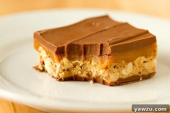 A tray of freshly made homemade Snickers bars, neatly cut and ready to be enjoyed, showing their perfect layers.