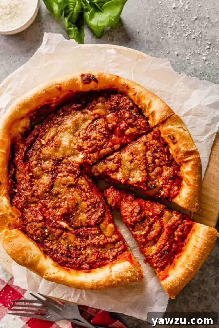 A Chicago-style deep-dish pizza with a slice removed, resting on parchment paper. Fresh basil leaves adorn the top left corner, highlighting the pizza's vibrant colors.