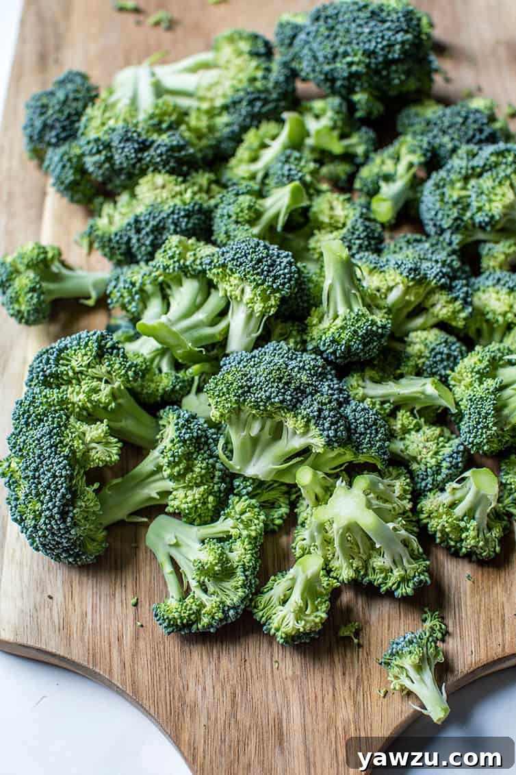 Fresh broccoli florets neatly arranged on a rustic wooden cutting board, ready for preparation.