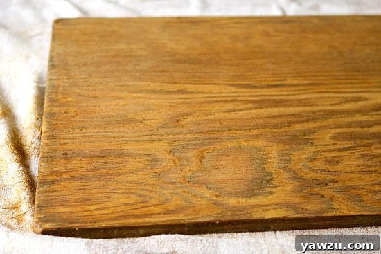 Wooden dough board after the second stage of sanding with medium-grit sandpaper, displaying further refinement and a visibly smoother surface