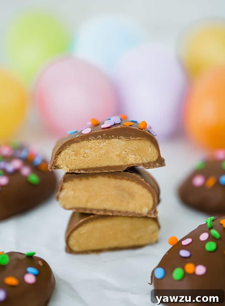 Homemade Peanut Butter Eggs, cut in half to reveal their creamy interior, beautifully arranged with colorful Easter eggs in the background.