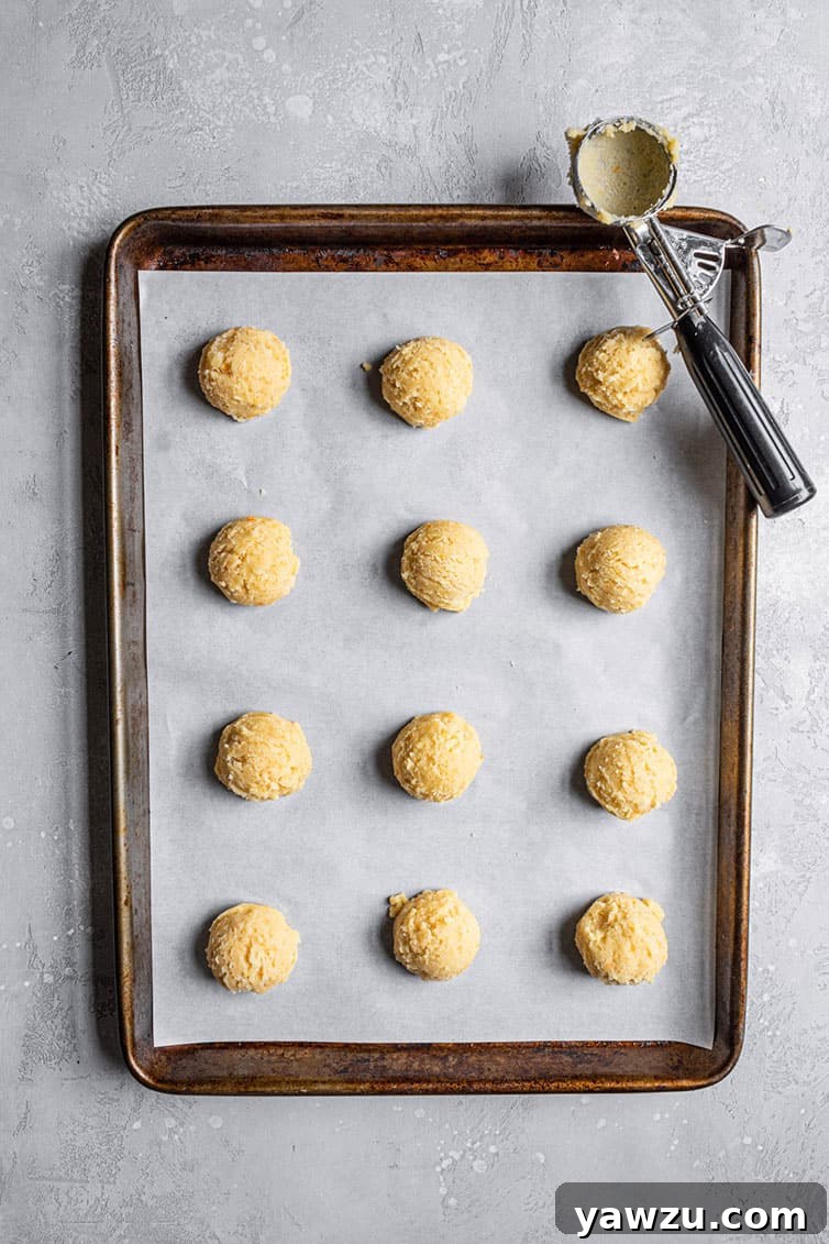 A baking sheet filled with perfectly scooped balls of orange cookie dough, ready for the oven.