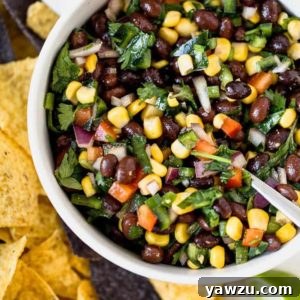 A bowl of homemade black bean salsa with tortilla chips on the side, ready to serve.