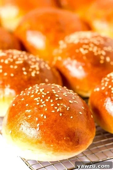 Two soft, tender homemade hamburger buns resting on a wire rack
