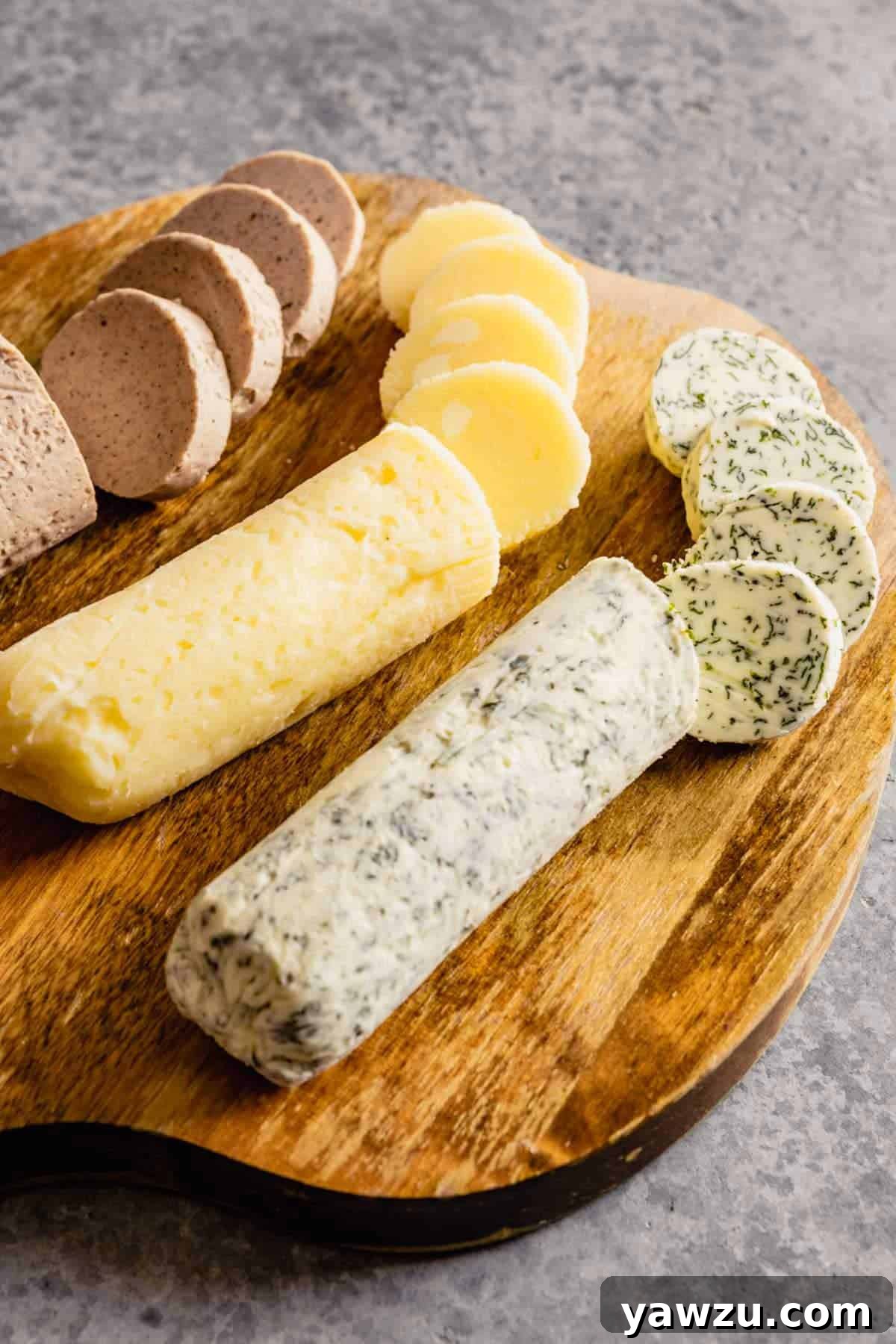 A beautiful wooden cutting board displaying artfully sliced rounds of Herb, Vanilla-Cinnamon, and Honey Compound Butters, ready to be enjoyed.