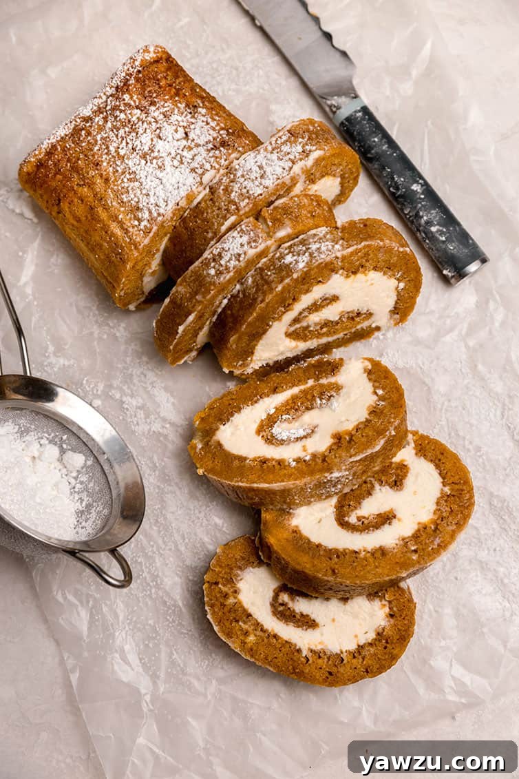 Beautifully sliced pumpkin roll showing its distinct spiral and creamy filling, ready for serving.