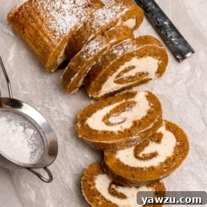 A perfectly coiled pumpkin roll, showing off its generous cream cheese filling, ready to be sliced and served.