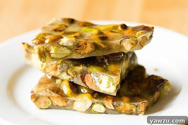 Beautifully broken pieces of golden Pistachio Brittle on a white surface, ready to be enjoyed.