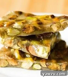 Pistachio Brittle close-up, showcasing its crunchy texture and vibrant green nuts embedded in the golden candy.