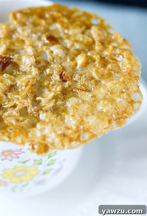 Multiple almond lace cookies stacked and displayed on a white plate