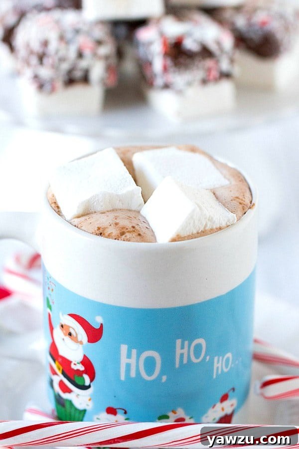 A close-up shot of several homemade peppermint marshmallows, perfectly cubed and lightly dusted with powdered sugar, sitting on a wooden surface.