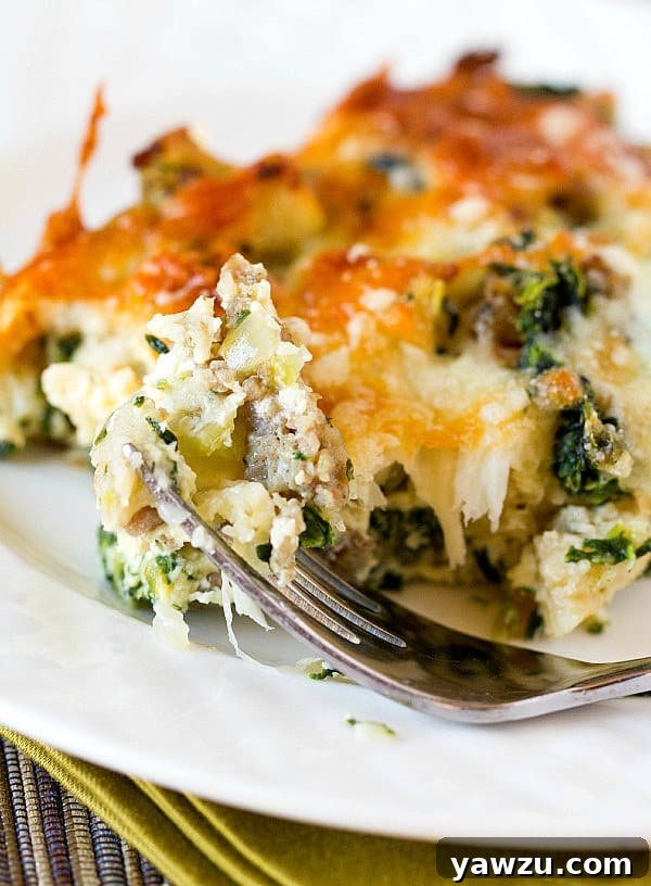 Slice of Cheesy Sausage Spinach Bake on a plate with more casserole in the background