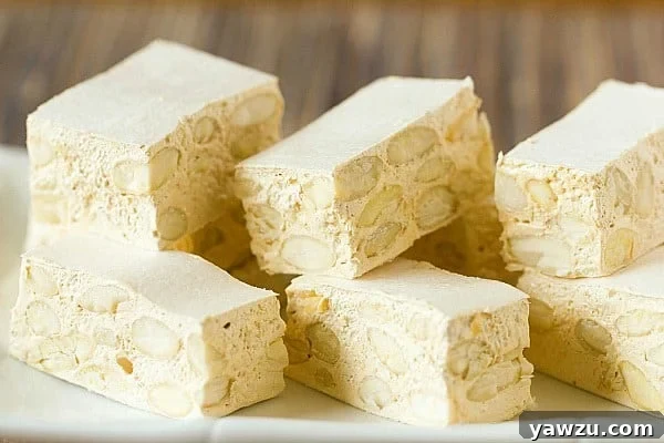 Delicious homemade torrone squares on a white surface.