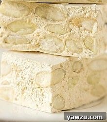 Homemade Torrone pieces on a small white plate.