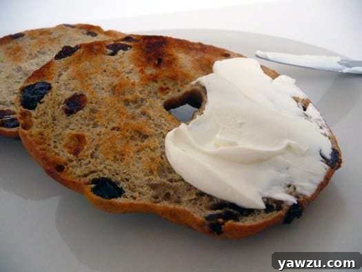 Cinnamon raisin bagel cut in half with cream cheese spread generously.