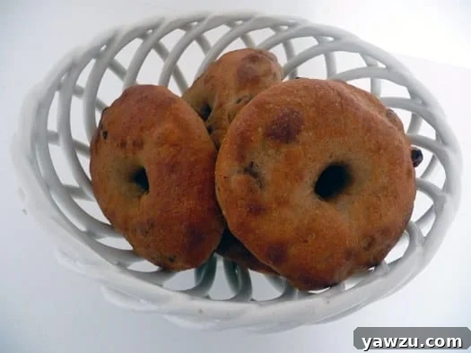 A bowl filled with freshly baked, golden-brown cinnamon raisin bagels.
