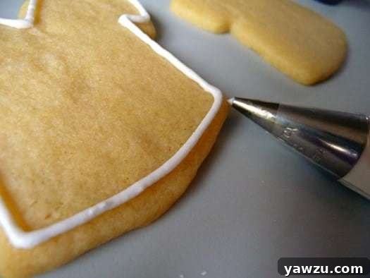 Using a piping tip to pipe a border of royal icing onto a sugar cookie.