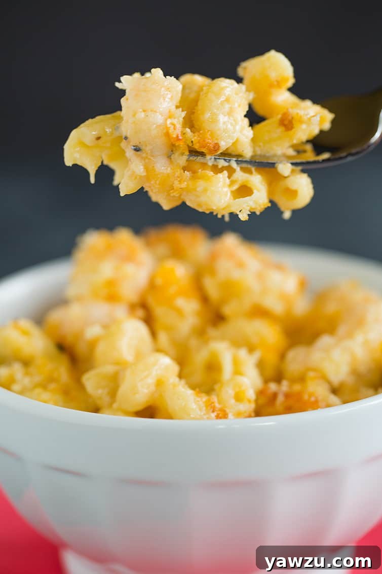 A close-up shot of a fork taking a large bite of Cajun shrimp macaroni and cheese, showing the gooey cheese and plump shrimp.