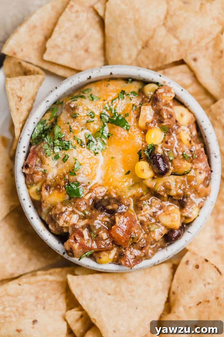 A small serving bowl filled with warm black bean dip, surrounded by a pile of golden tortilla chips.