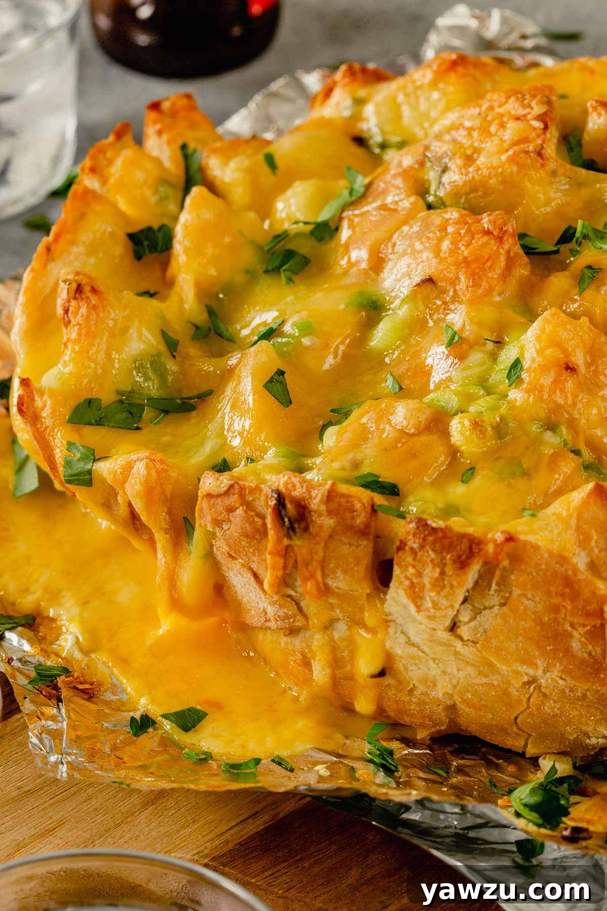 Side view of a golden-brown pull-apart bread with cheese oozing from the crevices.