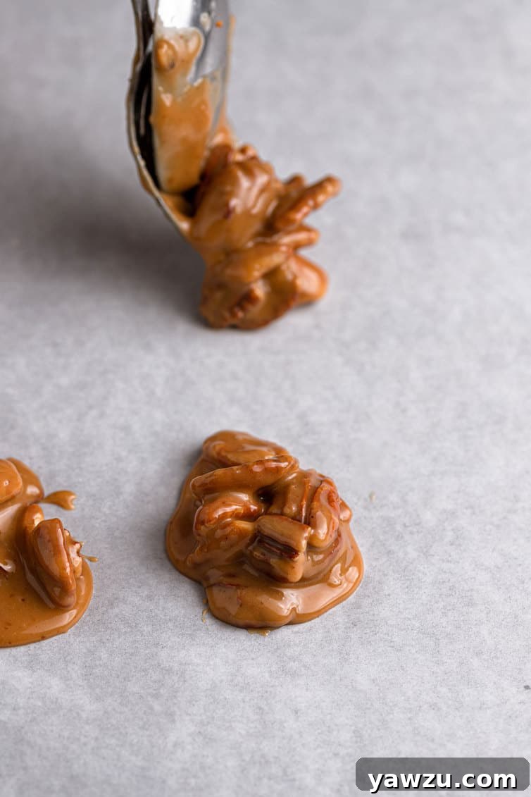 Individual scoops of pecan pralines carefully spooned onto parchment paper, cooling and setting.