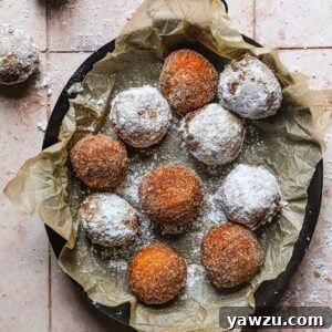 Overhead photo of fried zeppole, some coated in powdered sugar, others in cinnamon sugar.