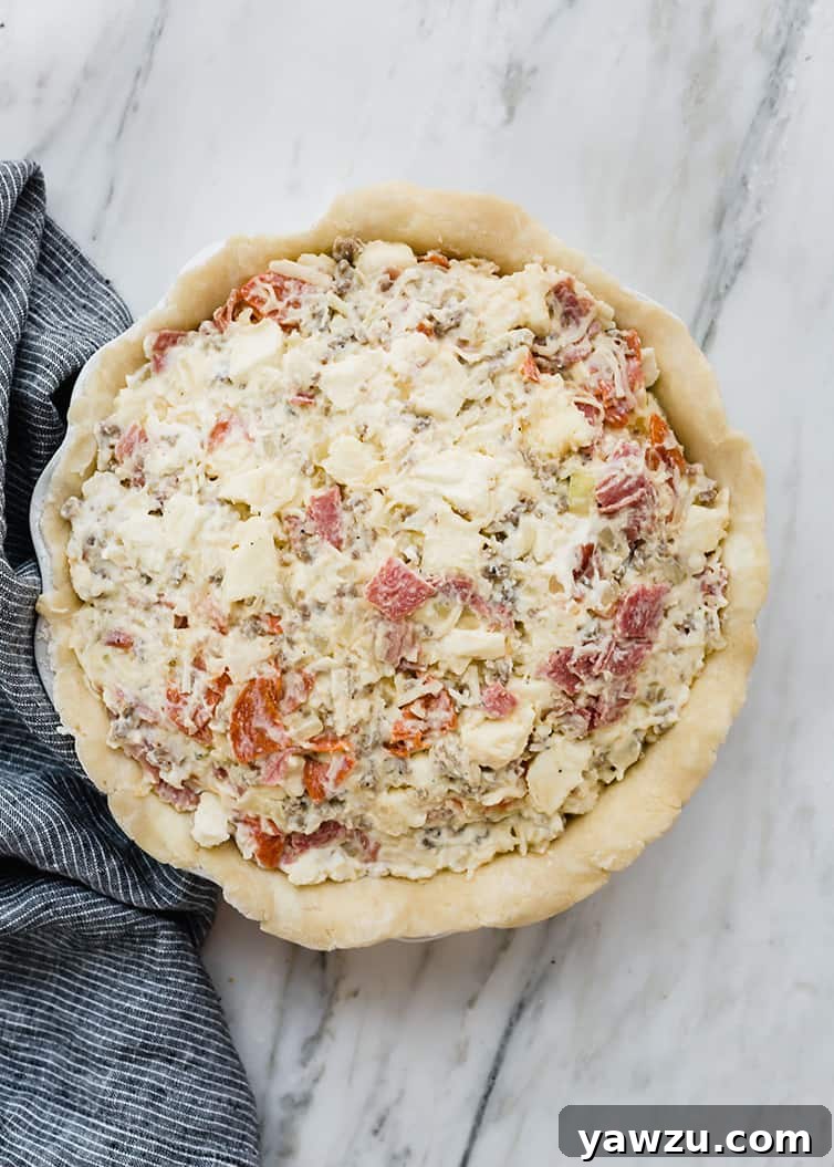 An assembled Italian Easter pie without the top crust, showcasing the generous, mounded filling of various meats and cheeses, ready for its final layer of dough.