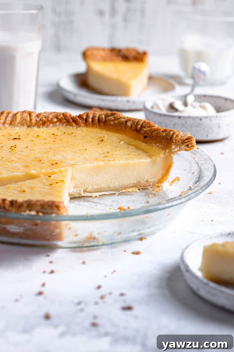 Buttermilk pie in glass pie plate with one third missing.