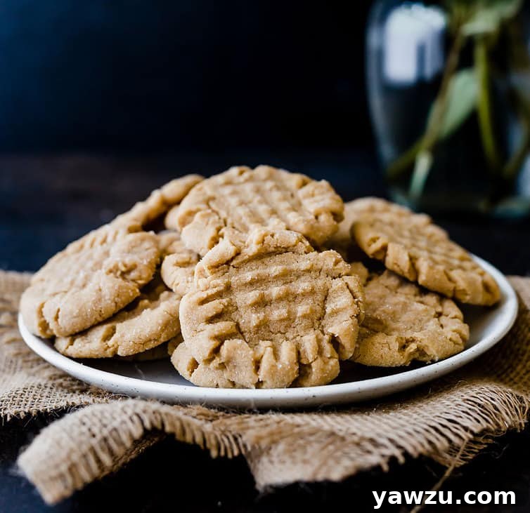 A beautifully arranged plate piled high with golden-brown peanut butter cookies, showcasing their inviting texture and shape.